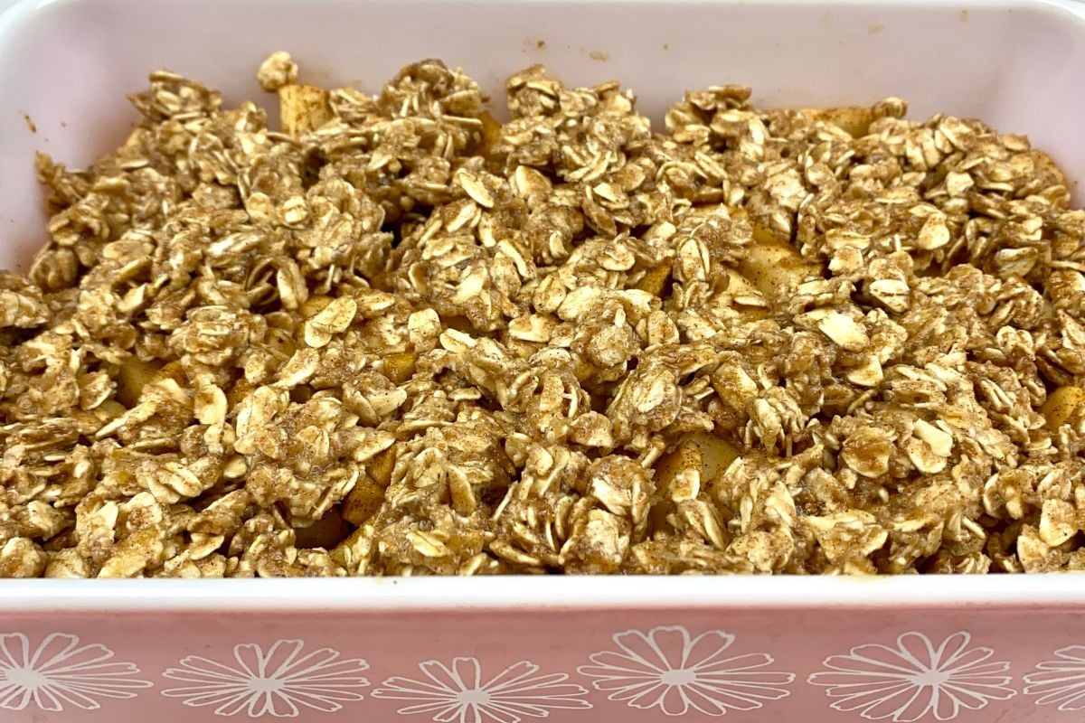 Oat topping over apple crisp in baking dish.