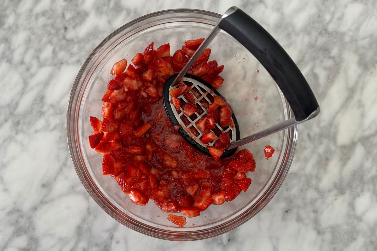 Lightly mashed strawberries in a bowl.