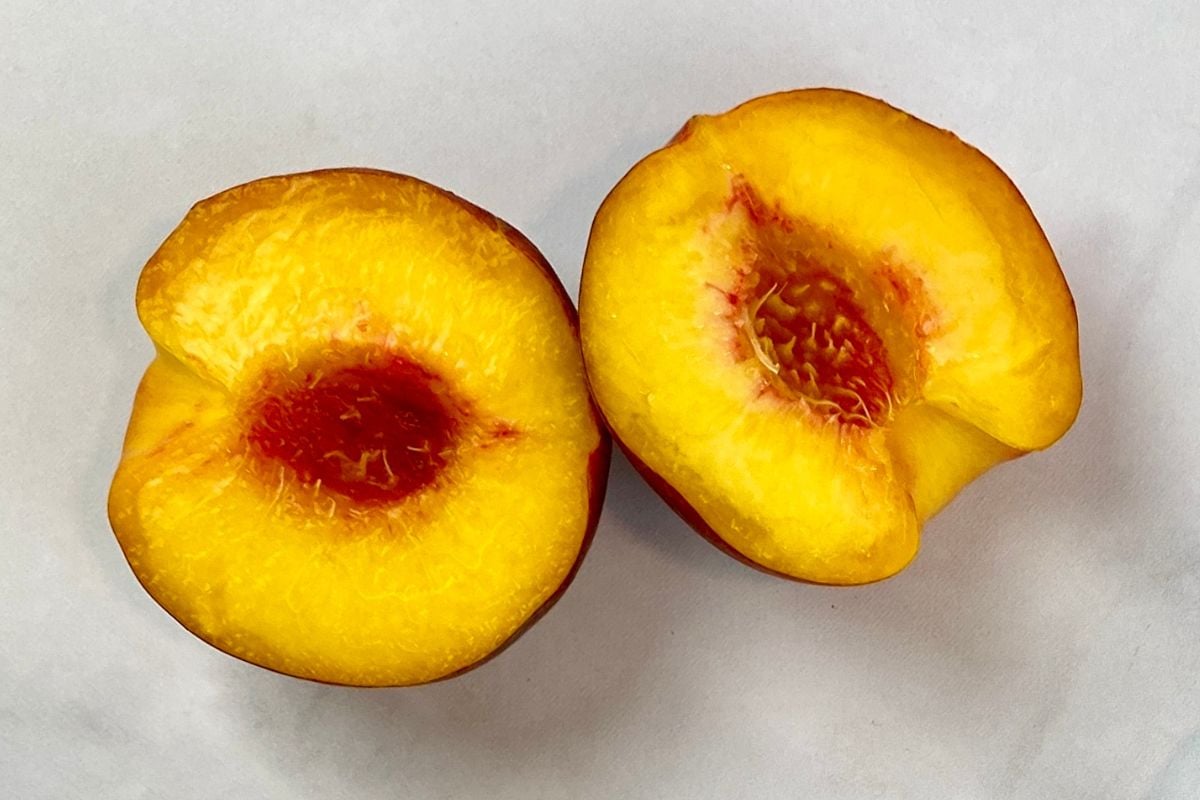 Fresh peach sliced in half with pit removed.