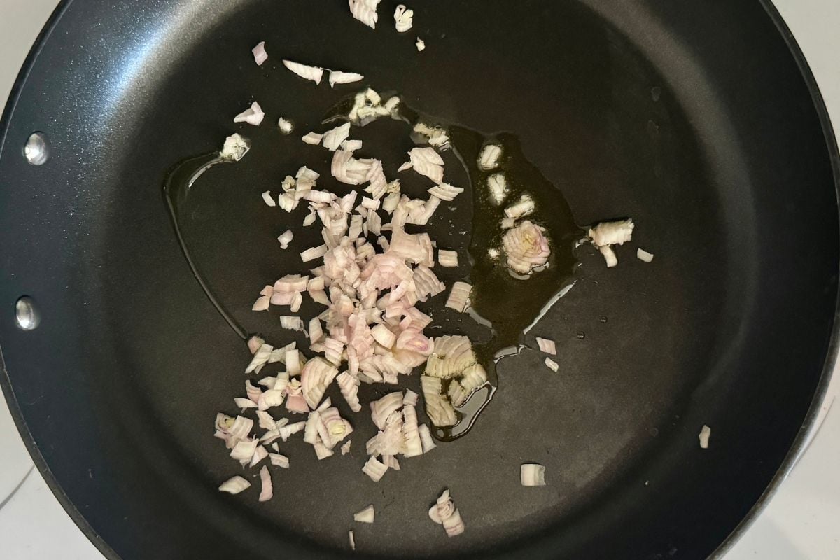 Chopped shallots and crushed garlic in a pan.