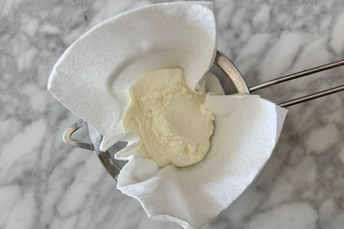 Drained ricotta cheese in strainer
