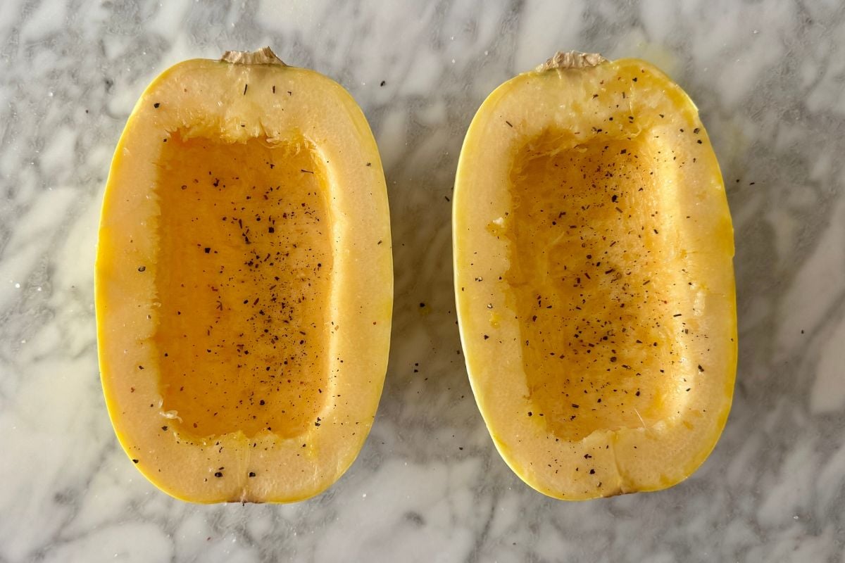 Seasoned spaghetti squash halves on baking sheet | Healthy Foodie Girl Seasoned spaghetti squash halves on baking sheet