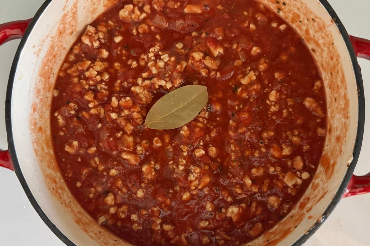 Bolognese sauce in a pot with a bay leaf