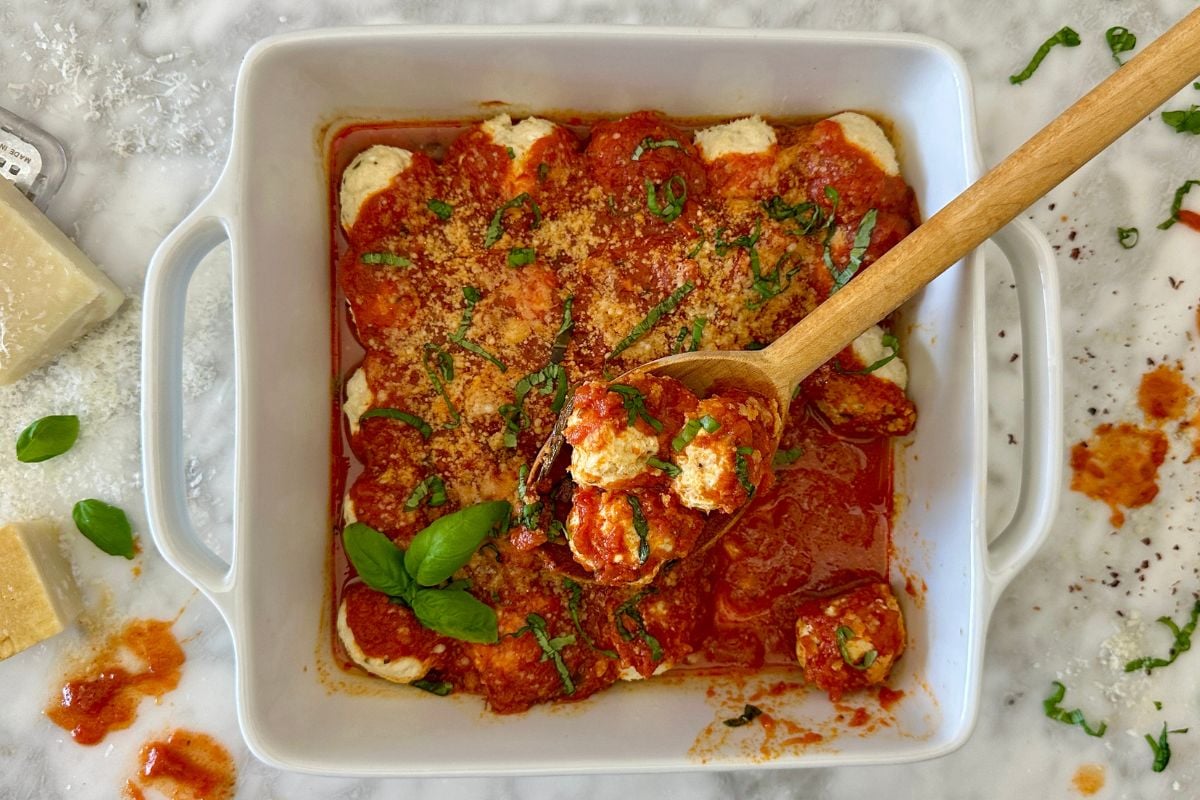 Cottage cheese meatballs in a serving dish with marinara and cheese.