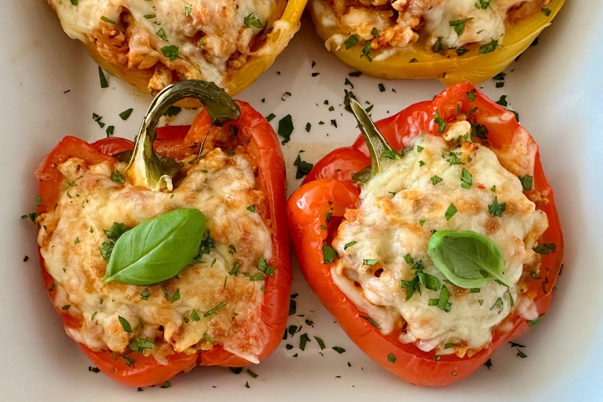 Cooked Italian stuffed peppers in baking dish topped with basil | Healthy Foodie Girl Cooked Italian stuffed peppers in a baking dish topped with basil.