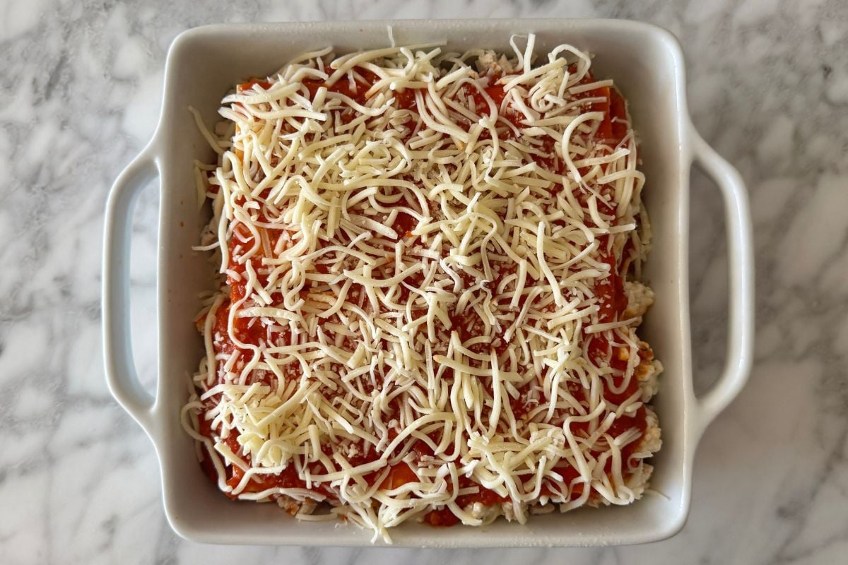 Cottage cheese lasagna topped with shredded cheese.
