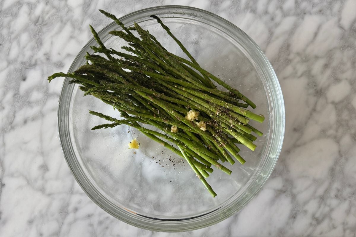 Asparagus with seasonings in a bowl.