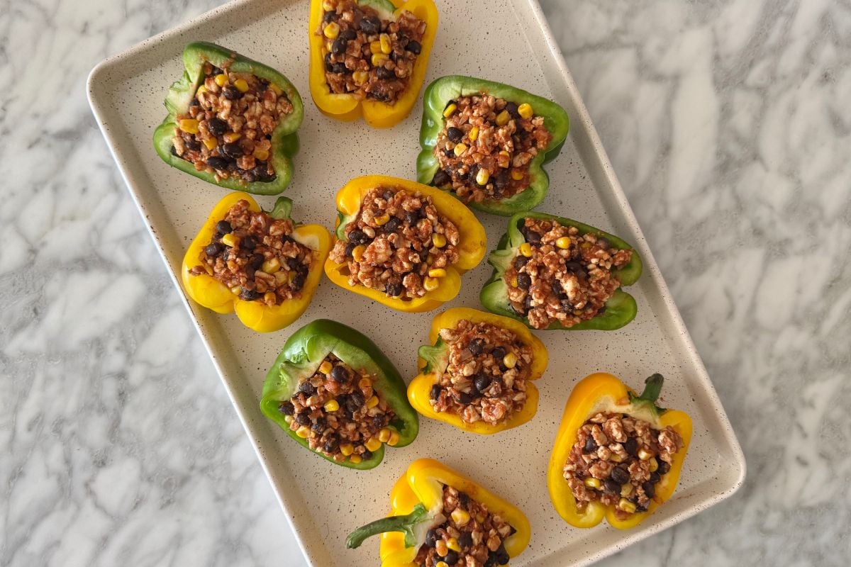 Bell peppers stuffed with filling on a sheet pan.