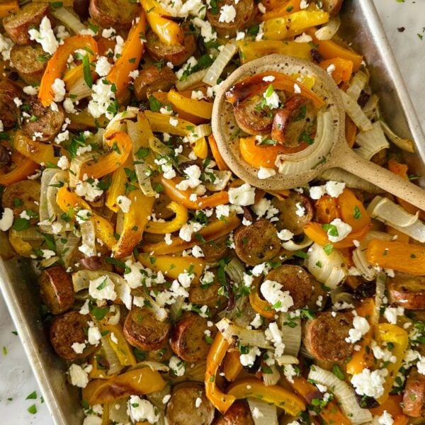 Mediterranean Sheet Pan Sausage and Peppers on a sheet pan topped with feta and parsley.