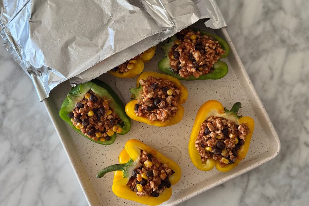 Mexican stuffed peppers on a sheet pan covered with foil.