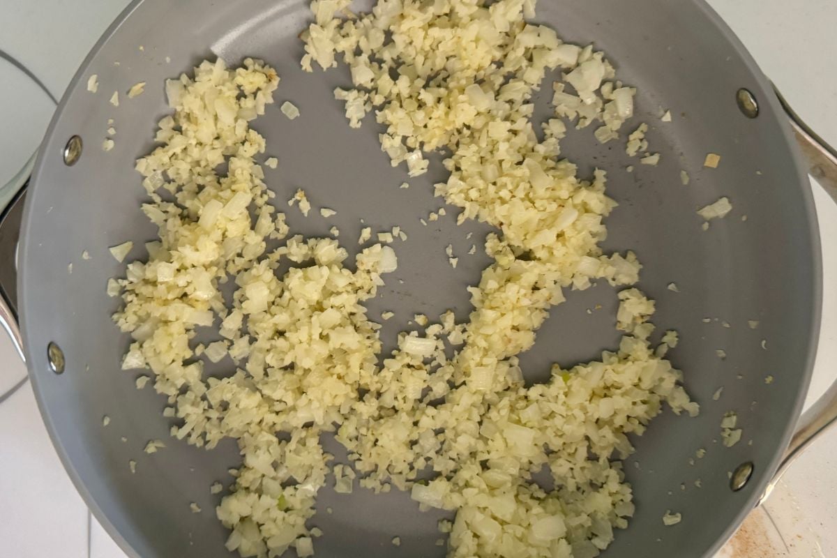 Onion garlic and cauliflower rice in a pan.