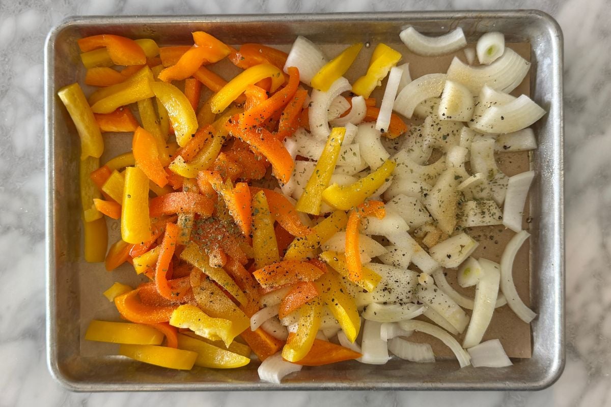Seasoned bell peppers and onions on a sheet pan.