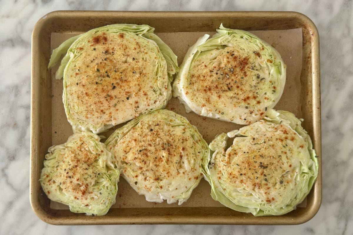 Seasoned cabbage steaks on a sheet pan.