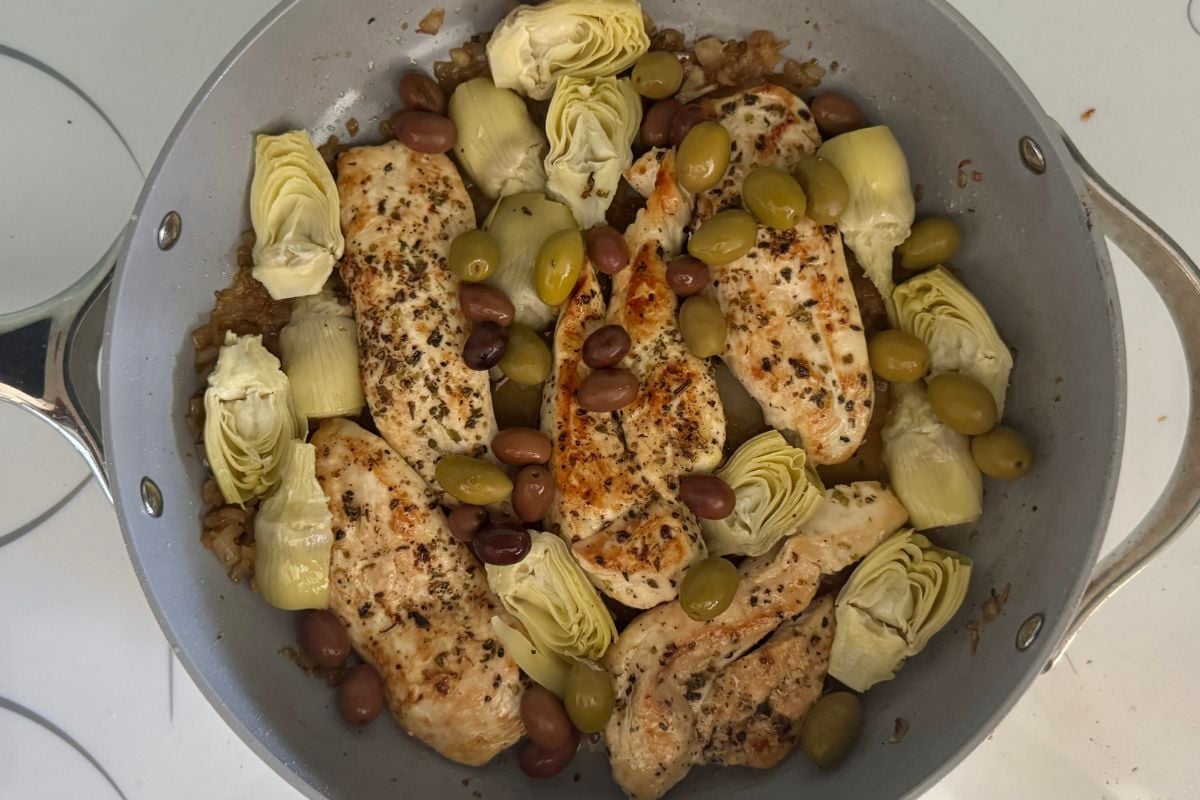 Chicken with artichokes and olives in a pan.