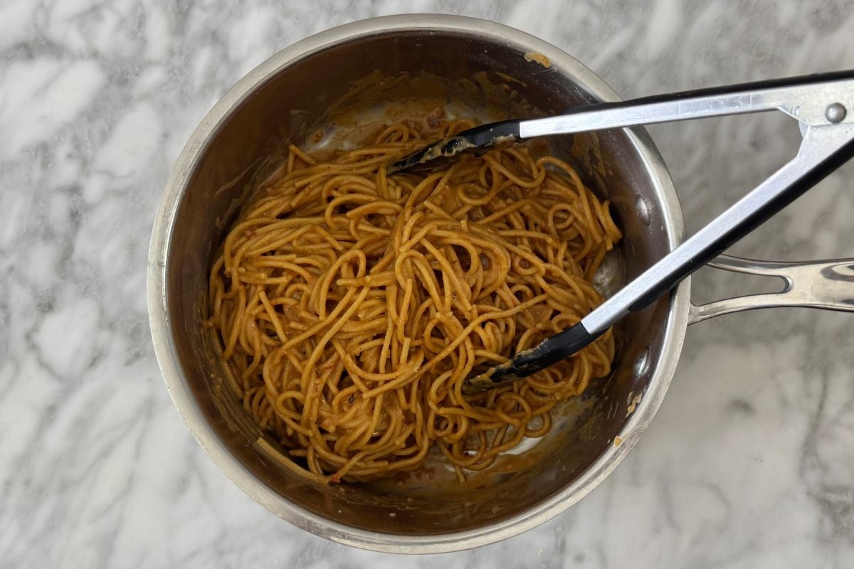 Coated spicy peanut noodles in a saucepan.