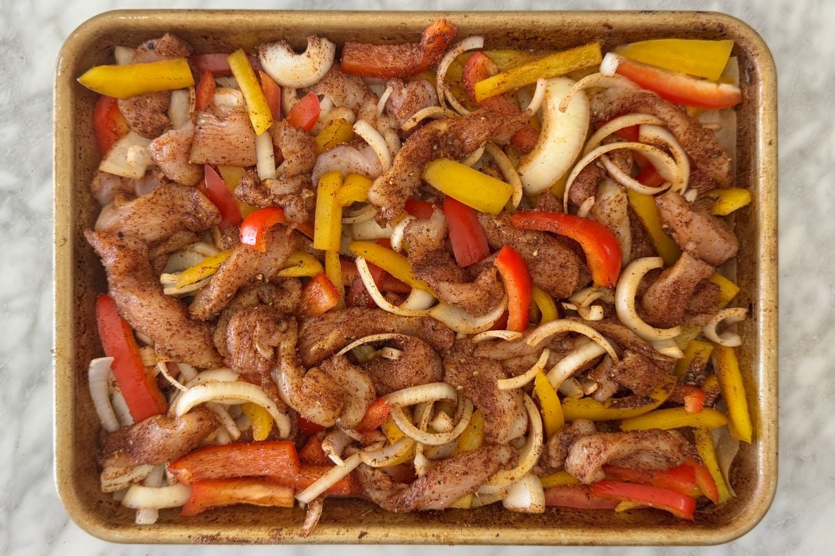 Seasoned chicken fajitas mixture on a sheet pan.
