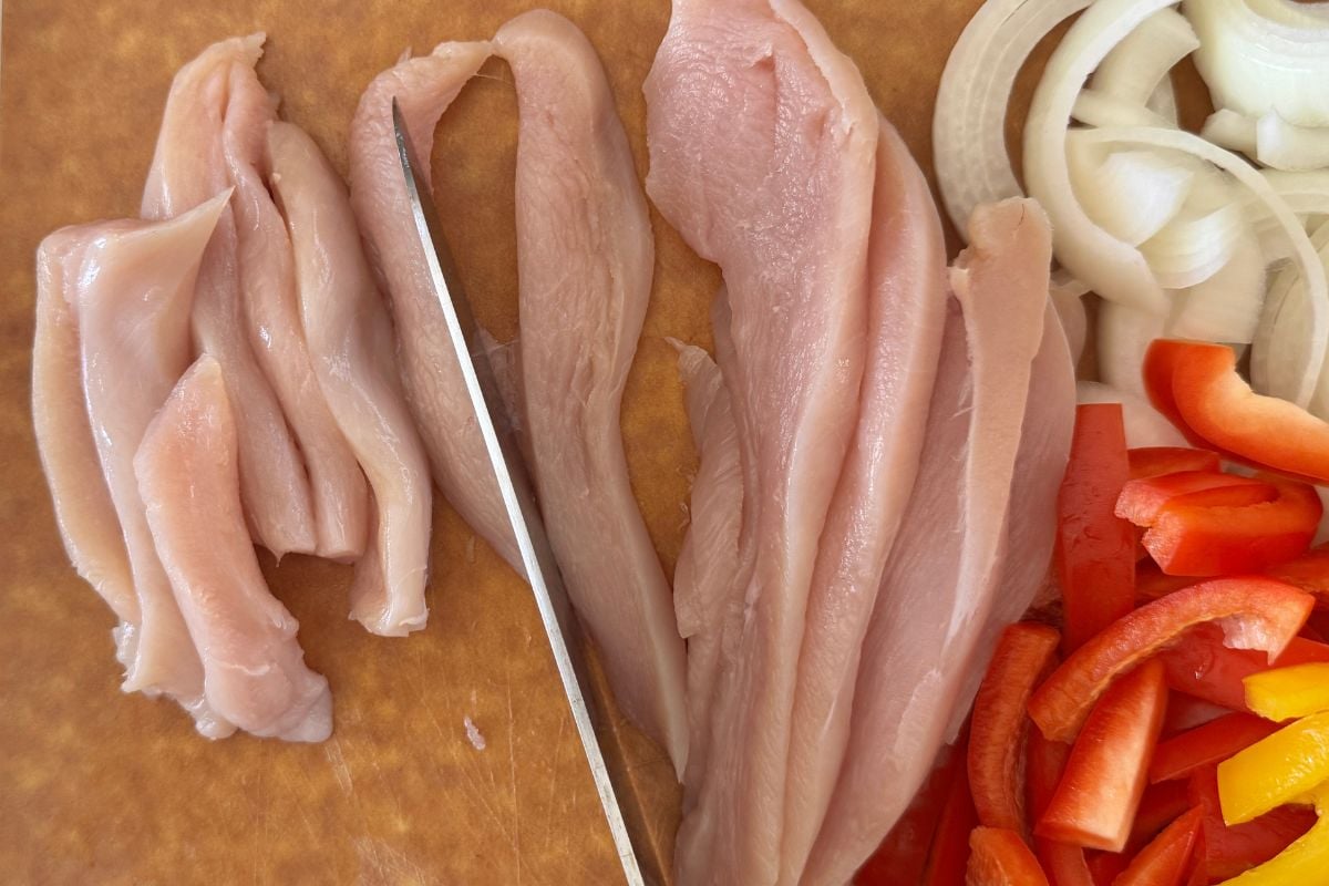 Sliced chicken for fajitas on cutting board.