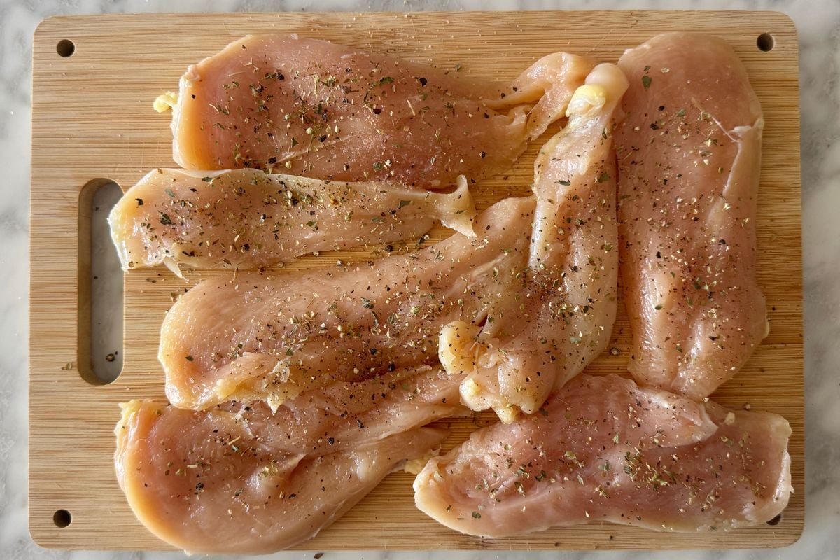 Sliced seasoned chicken breast on a cutting board.