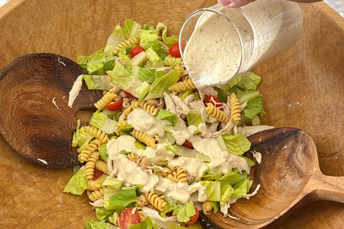 Caesar dressing poured over pasta salad.