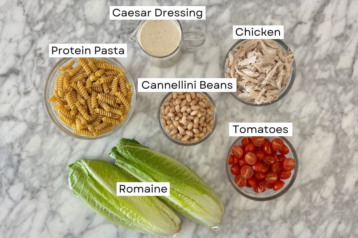 Ingredients for high protein chicken Caesar pasta salad in bowls.