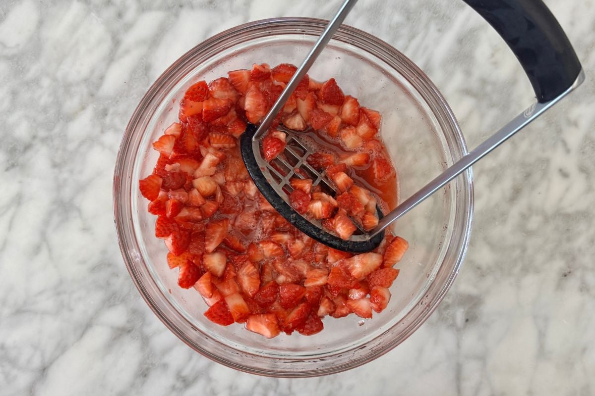 Lightly mashed strawberries in a bowl.