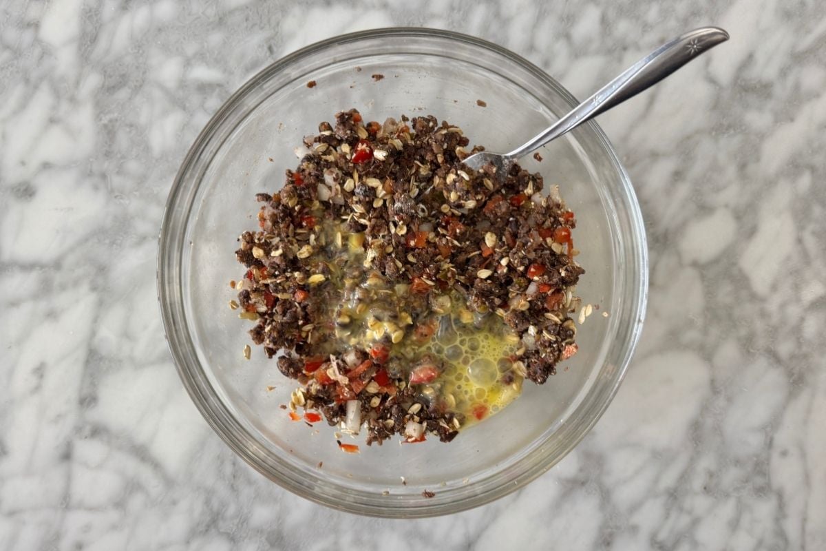 Whisked egg in bowl with chipotle black bean burger mixture.