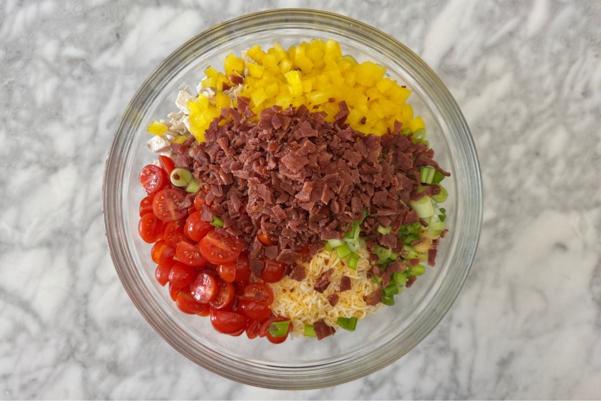 Bacon and tomatoes and bell peppers in a bowl with protein pasta in bowl.