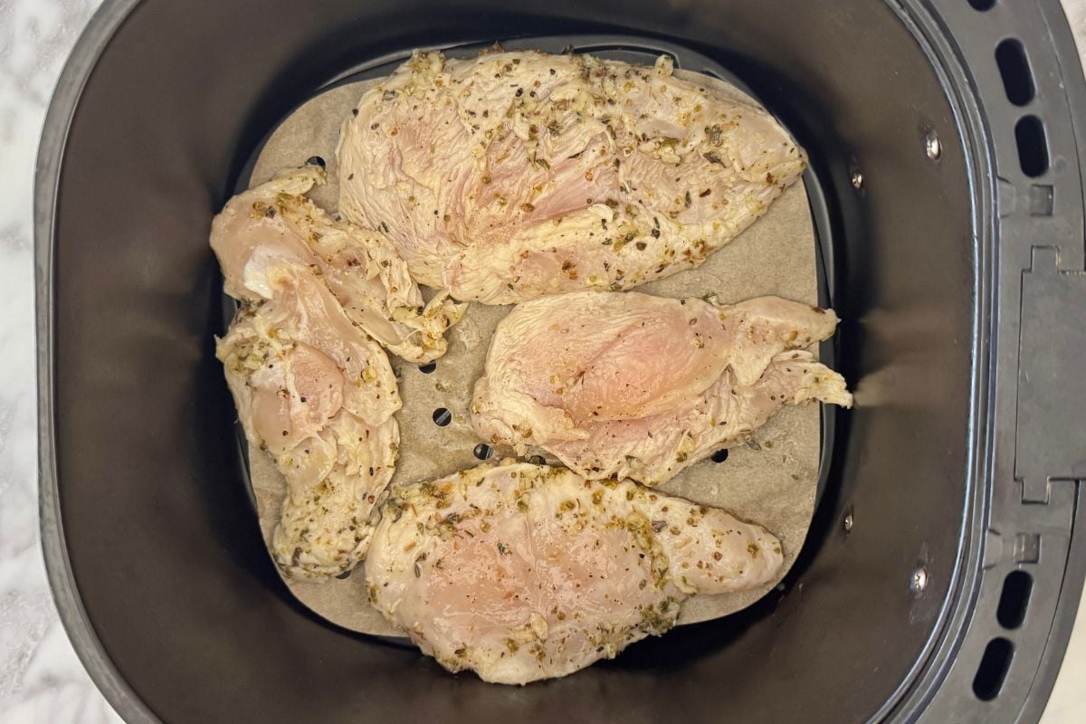 Marinated chicken in the air fryer basket.