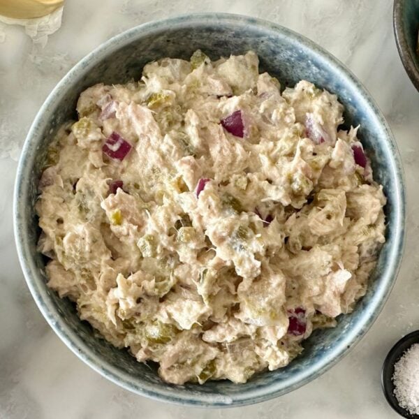 Jalapeño tuna salad recipe in a bowl | Healthy Foodie Girl Bowl of creamy chicken salad with diced red onions and pickles, surrounded by prep bowls of onions and spices on a light countertop