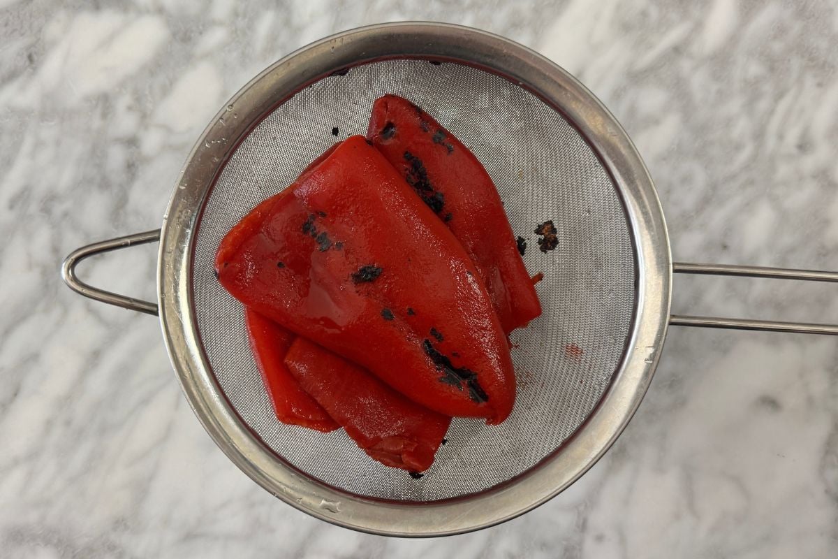 Drained roasted red peppers in strainer | Healthy Foodie Girl Drained roasted red peppers in strainer.