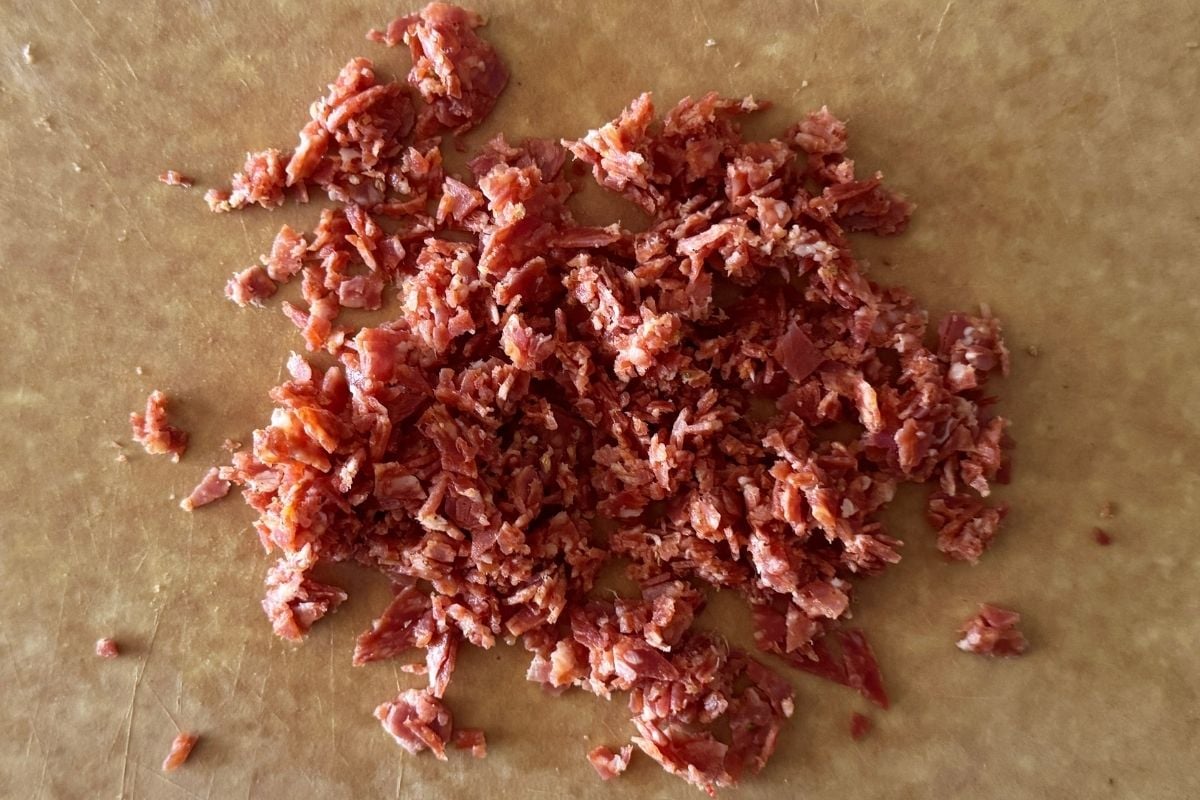 Roughly chopped pepperoni on cutting board.