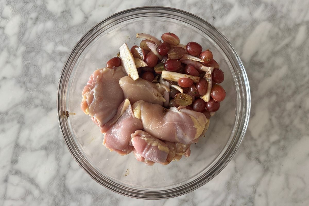 Sliced shallots and grapes in bowl with balsamic vinegar mixture.