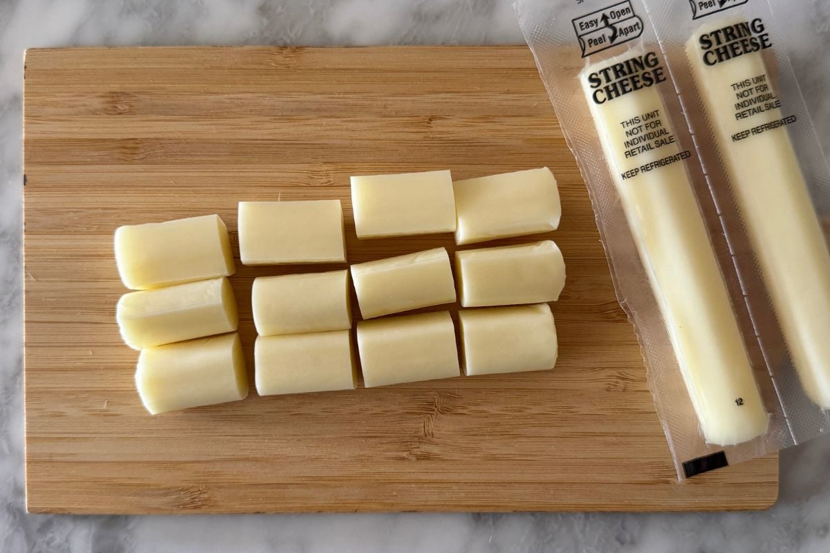 String cheese cut into pieces on cutting board.